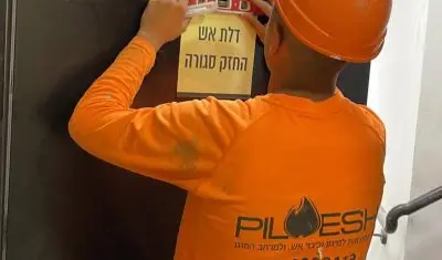 עובד של פילו אש מתקין שילוט בטיחות בפרויקט מגורים של בשוהם.