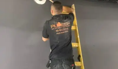 עובד של פילו אש על סולם עוסק באיטום מעברי אש.